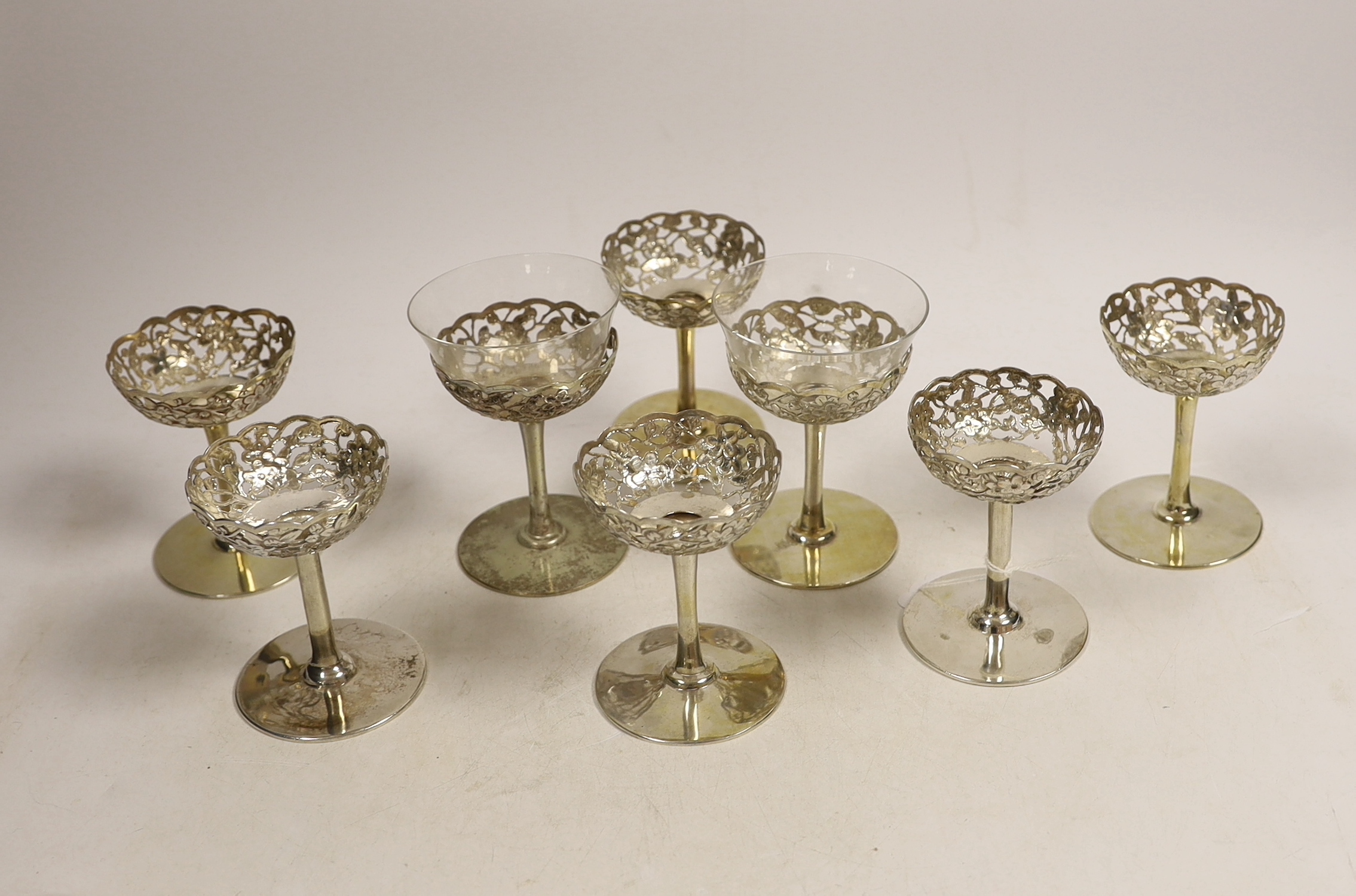 A matched set of eight pierced white metal coupes, two with glass inserts, six stamped with Chinese character mark, two stamped 'silver', height 87mm.